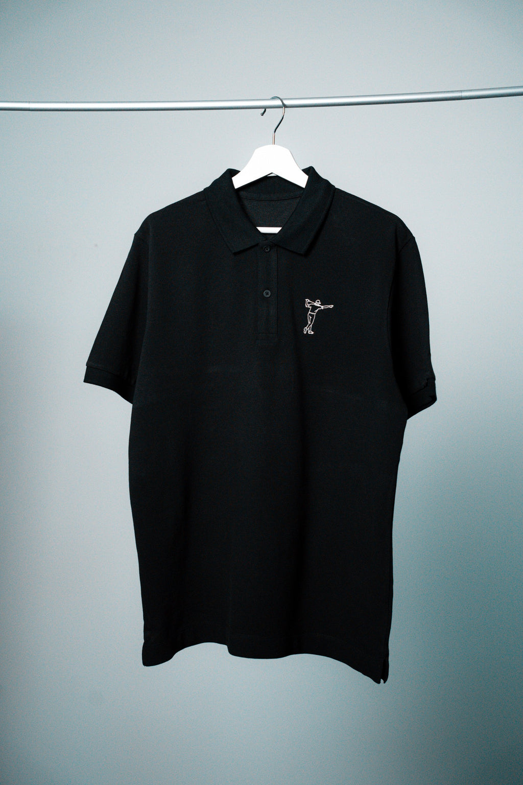 FOA black polo, front view on a hanger.
