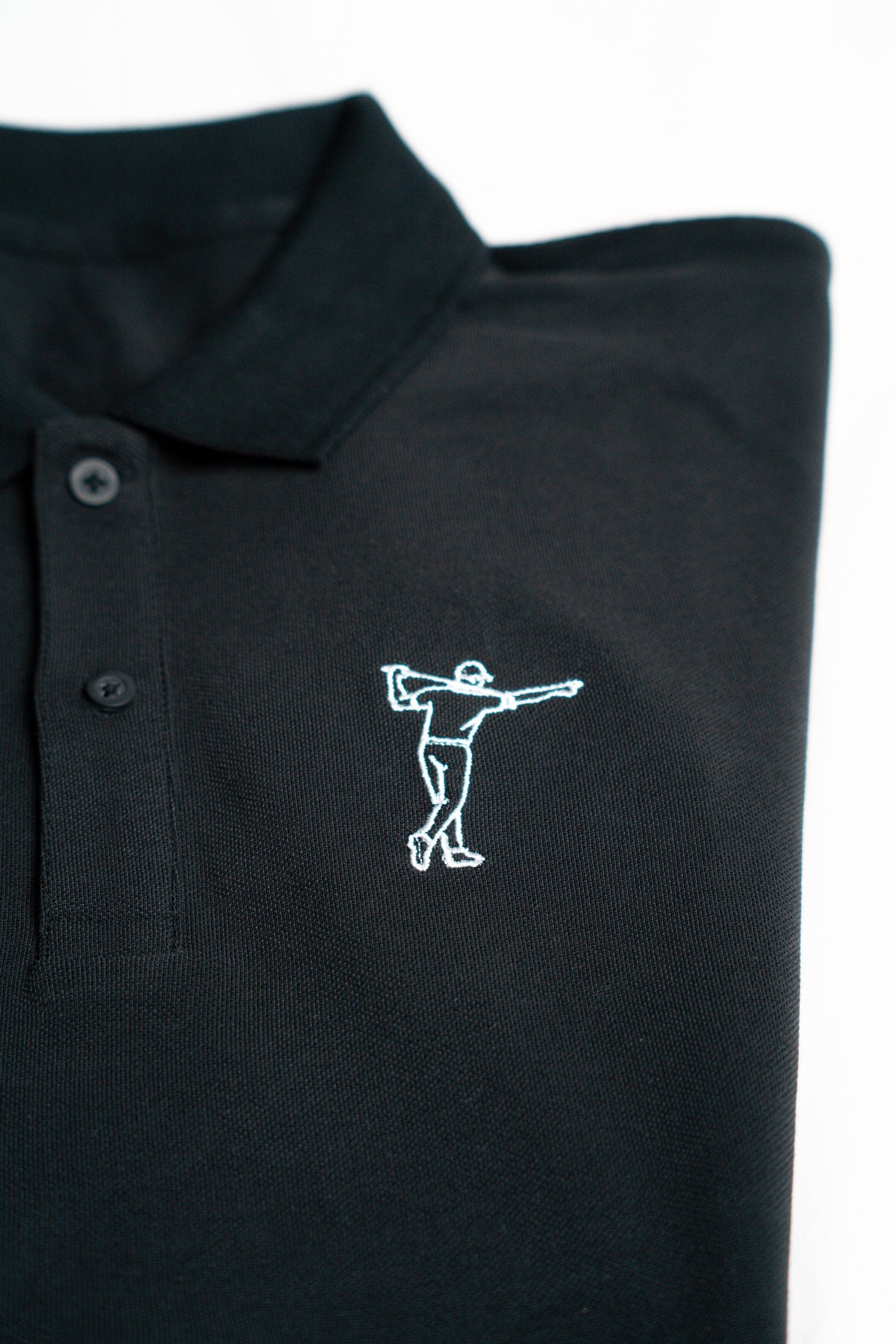 FOA black polo, close-up of the embroidered golfer and fabric.