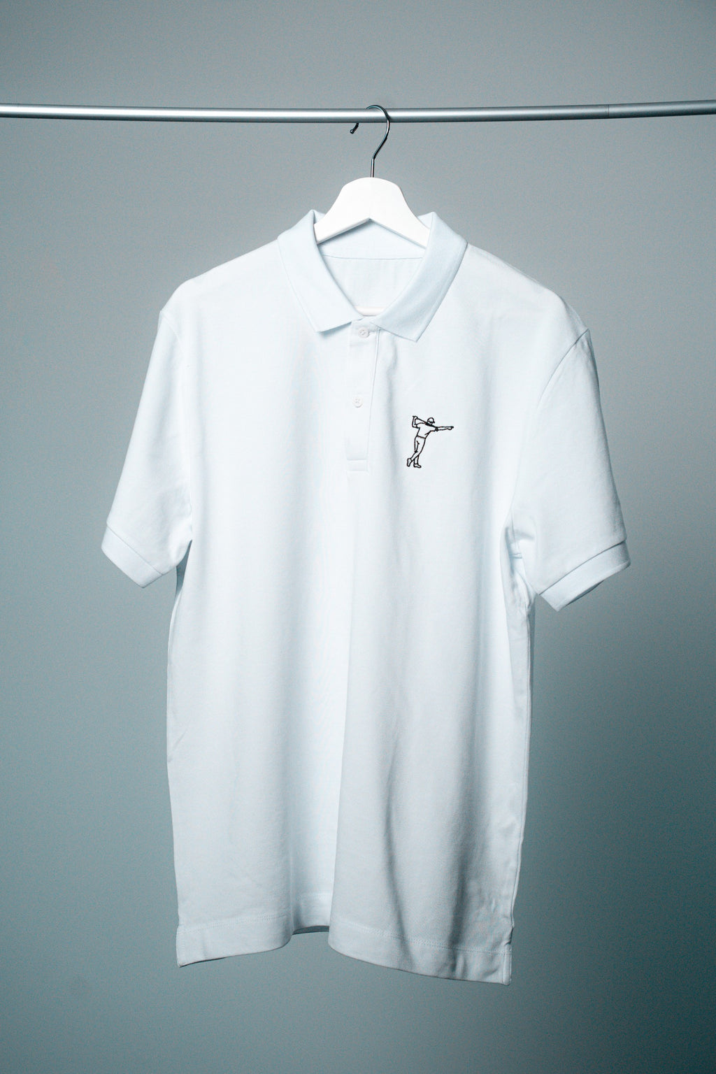 FOA white polo, front view on a hanger.