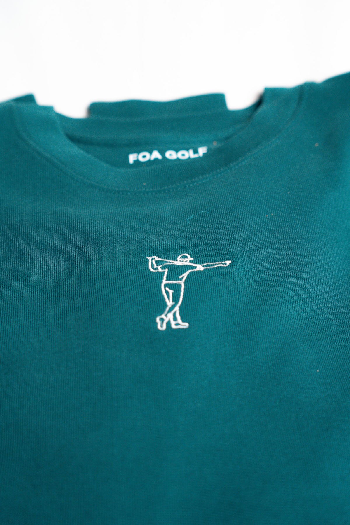 FOA green sweatshirt, close-up of the embroidered golfer and fabric.