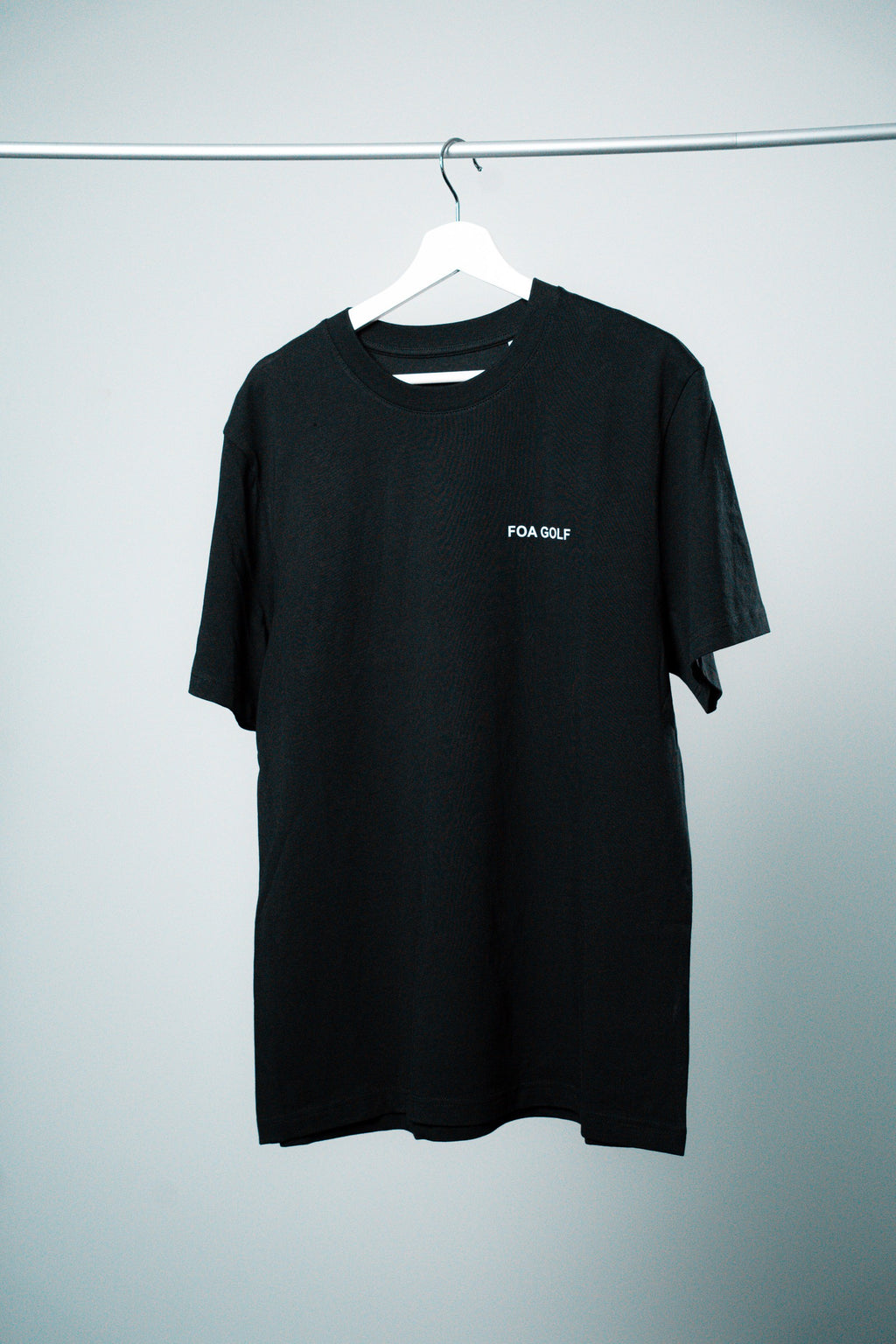 FOA black t-shirt, front view on a hanger.