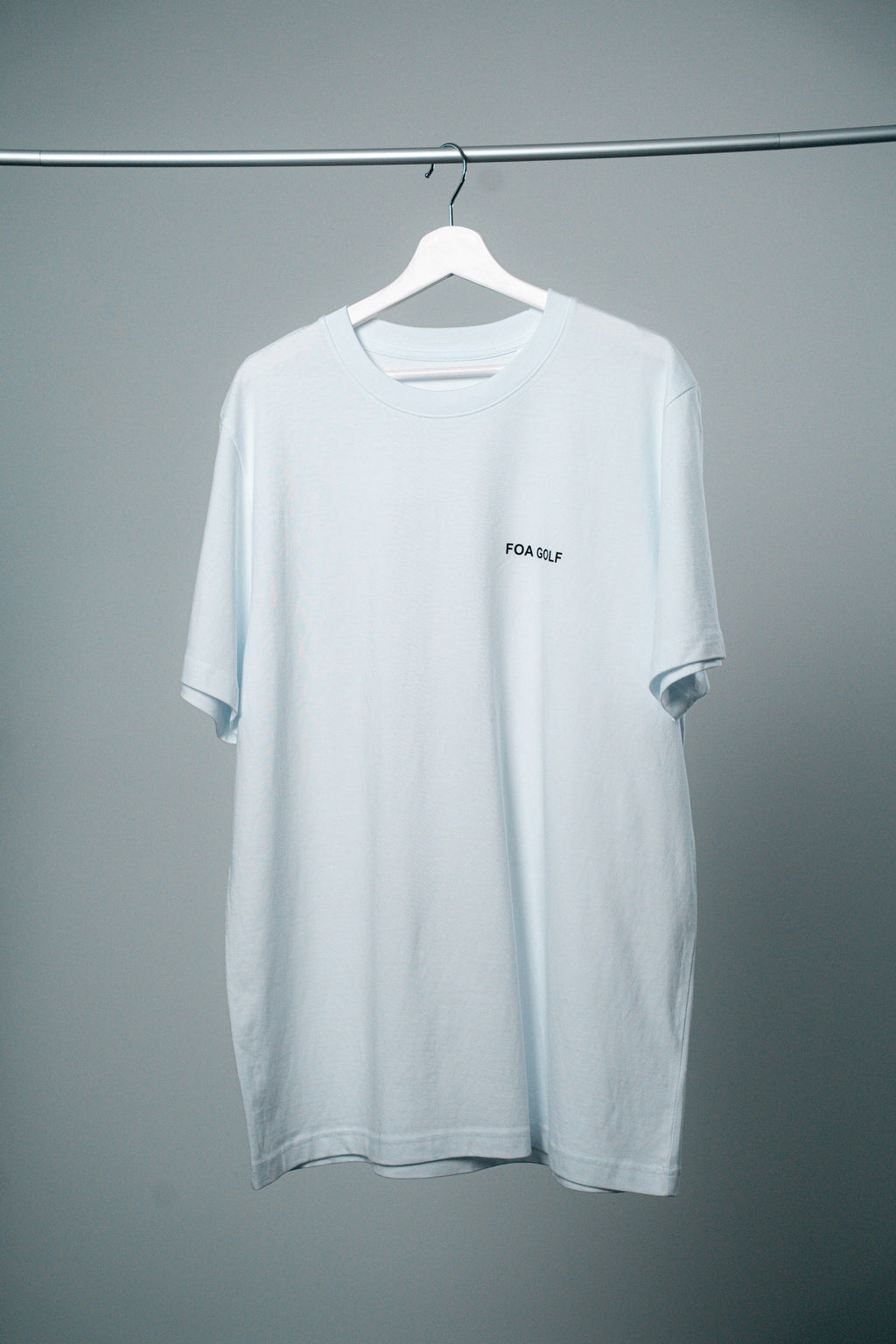 FOA white t-shirt, front view on a hanger.
